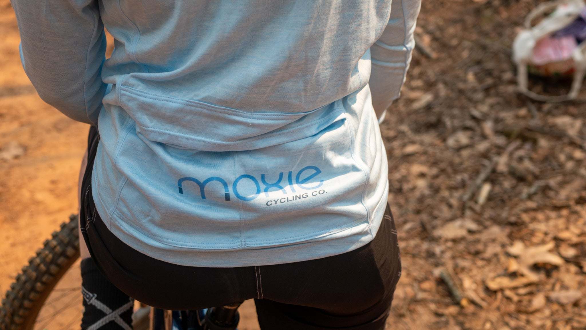 Moxie Sun Saver Hoodie with bike cog graphic worn on a biking trail.